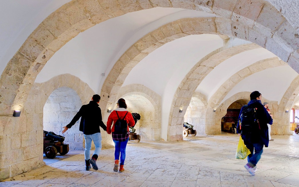 Visitors exploring the stone arches and cannons inside Belem Tower, Lisbon.