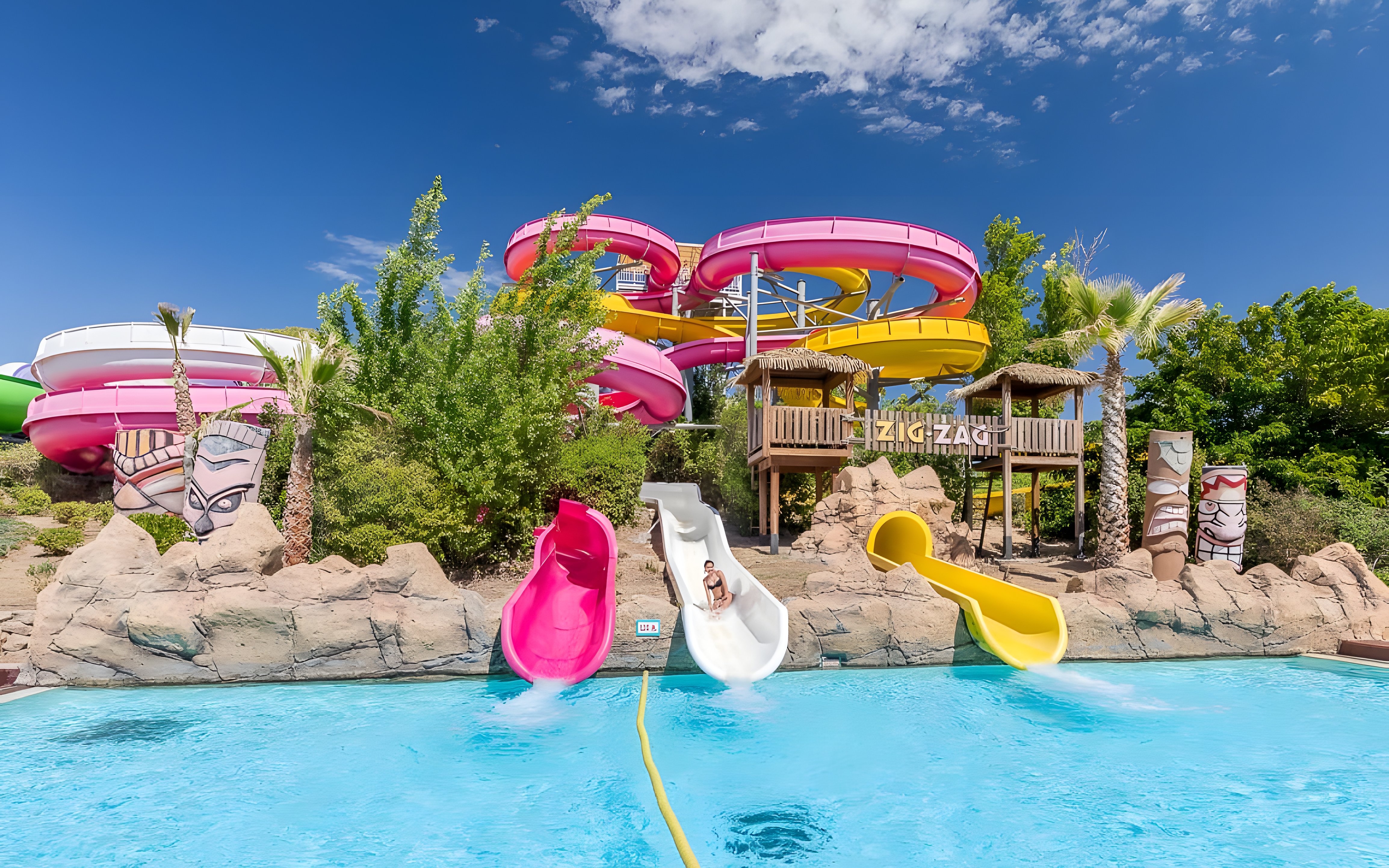 Zig zag water slide at Aquopolis Villanueva de la Cañada with colorful tubes and pool.