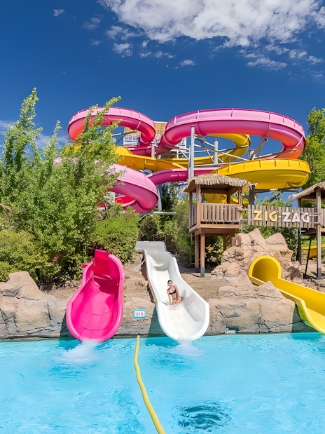 Zig zag water slide at Aquopolis Villanueva de la Cañada with colorful tubes and pool.