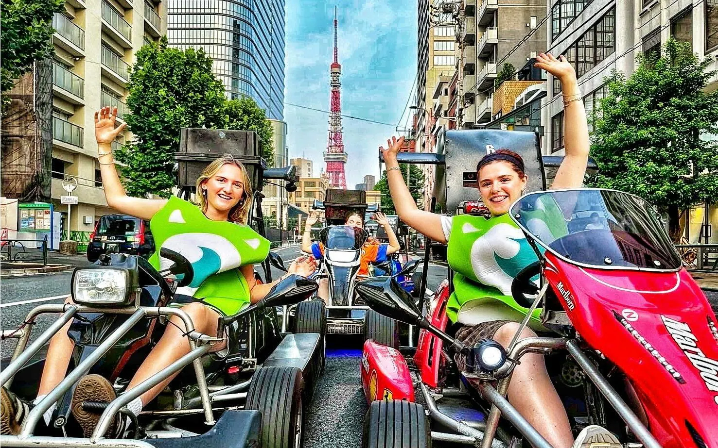 Go-kart riders in costume on Tokyo street with Tokyo Tower in background.