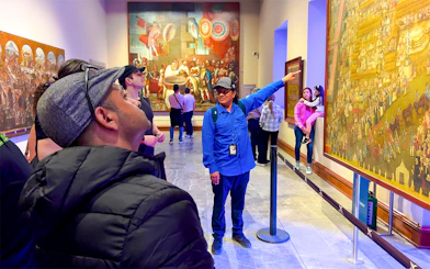 Tour guide explaining mural at anthropology museum, Mexico.