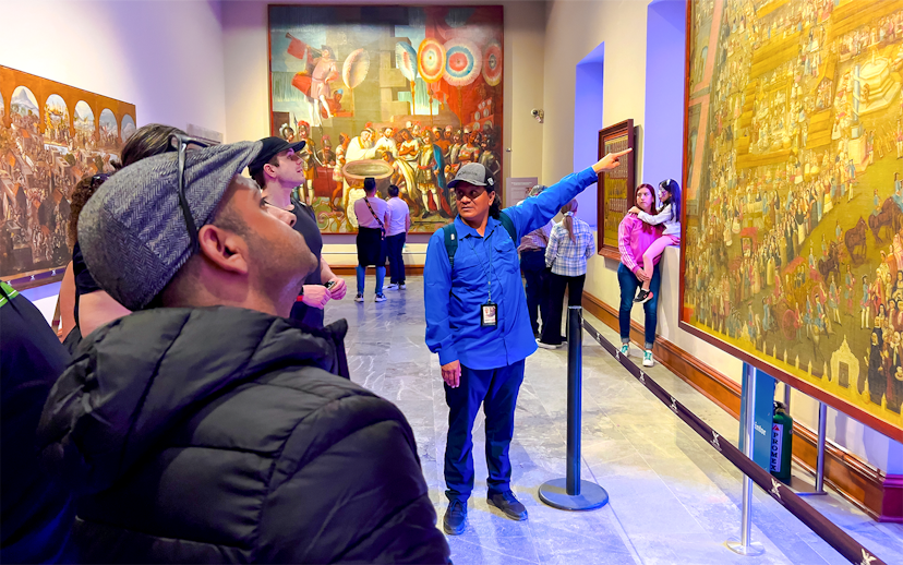 Tour guide explaining mural at anthropology museum, Mexico.