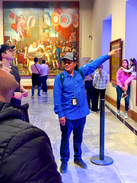 Tour guide explaining mural at anthropology museum, Mexico.