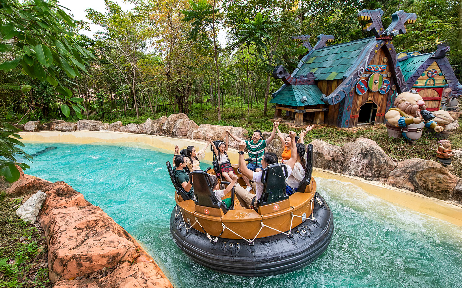 Group enjoying water ride at VinWonders Phu Quoc with themed buildings in background.