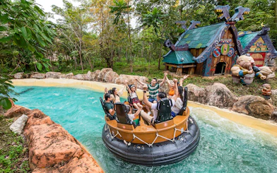 Group enjoying water ride at VinWonders Phu Quoc with themed buildings in background.