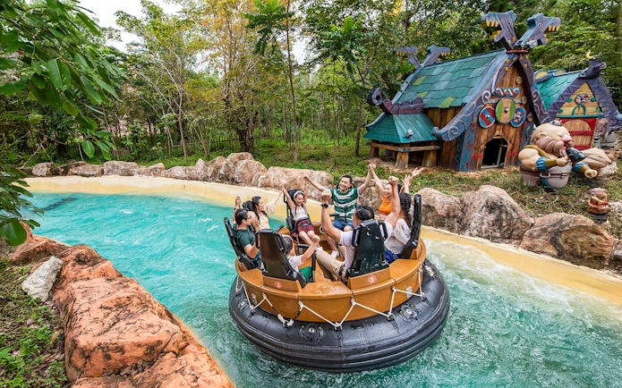 Group enjoying water ride at VinWonders Phu Quoc with themed buildings in background.
