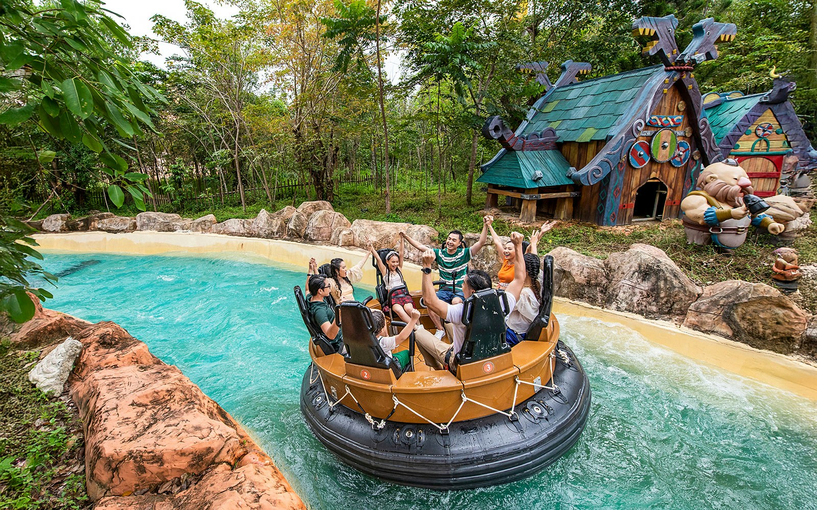 Group enjoying water ride at VinWonders Phu Quoc with themed buildings in background.