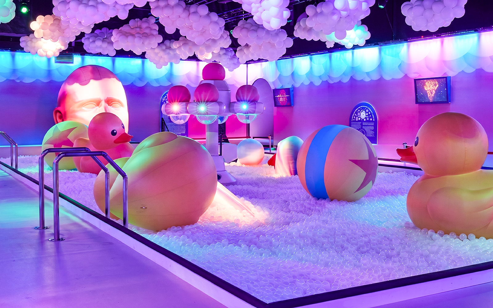 Interactive ball pit with giant rubber ducks and colorful lights at Bubble Planet Atlanta.
