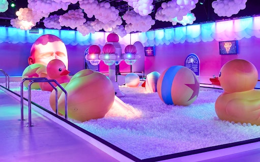 Interactive ball pit with giant rubber ducks and colorful lights at Bubble Planet Atlanta.