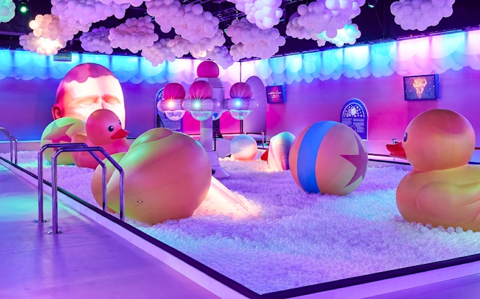 Interactive ball pit with giant rubber ducks and colorful lights at Bubble Planet Atlanta.