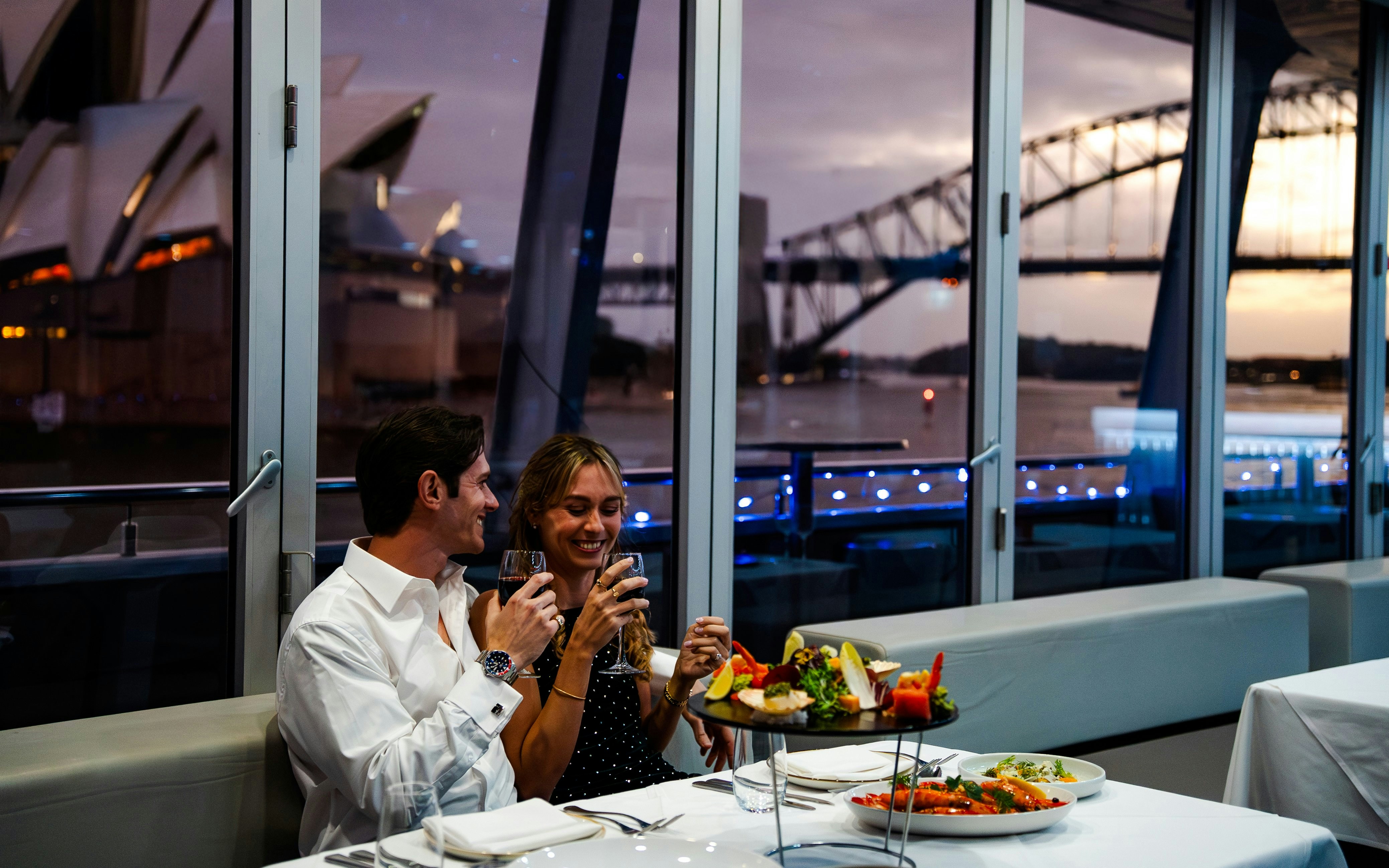 Couple enjoying dinner on a Sydney Harbour cruise with views of the Opera House and Harbour Bridge.
