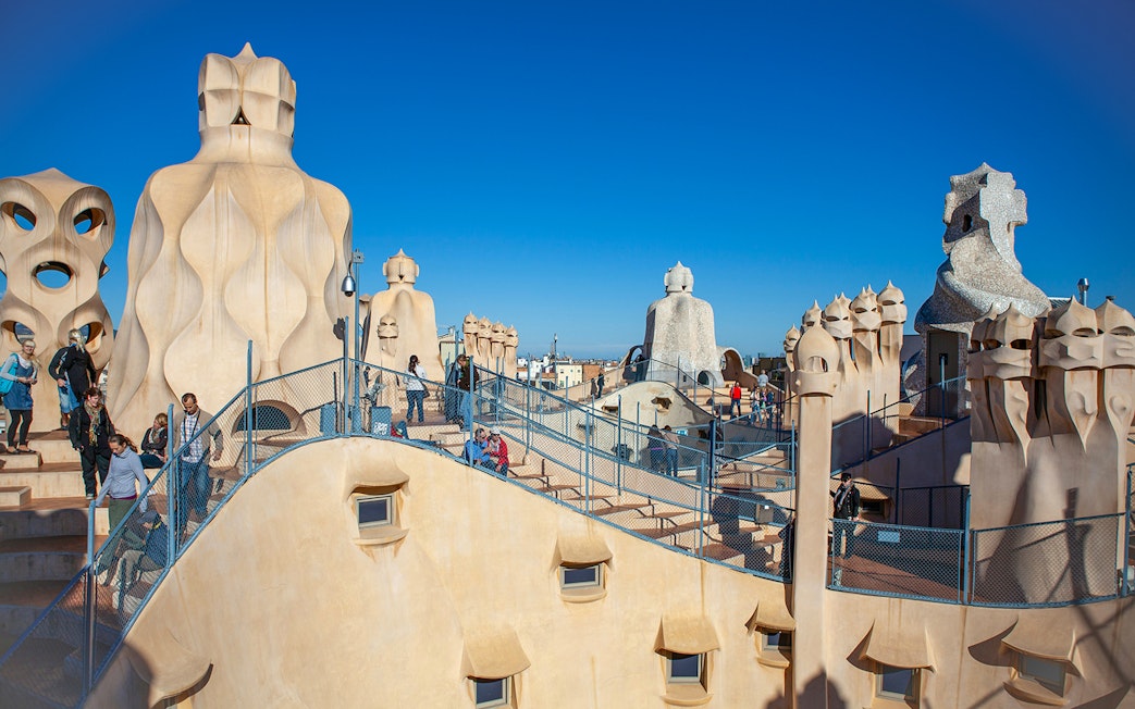 Rooftop of Casa Milà in Barcelona with tourists exploring Gaudí's unique chimneys.