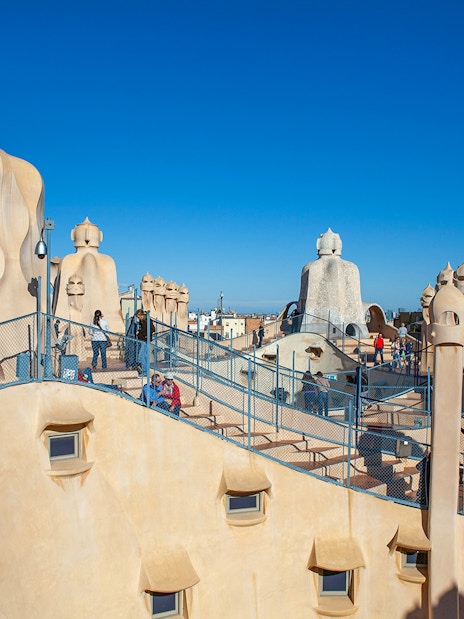 Rooftop of Casa Milà in Barcelona with tourists exploring Gaudí's unique chimneys.