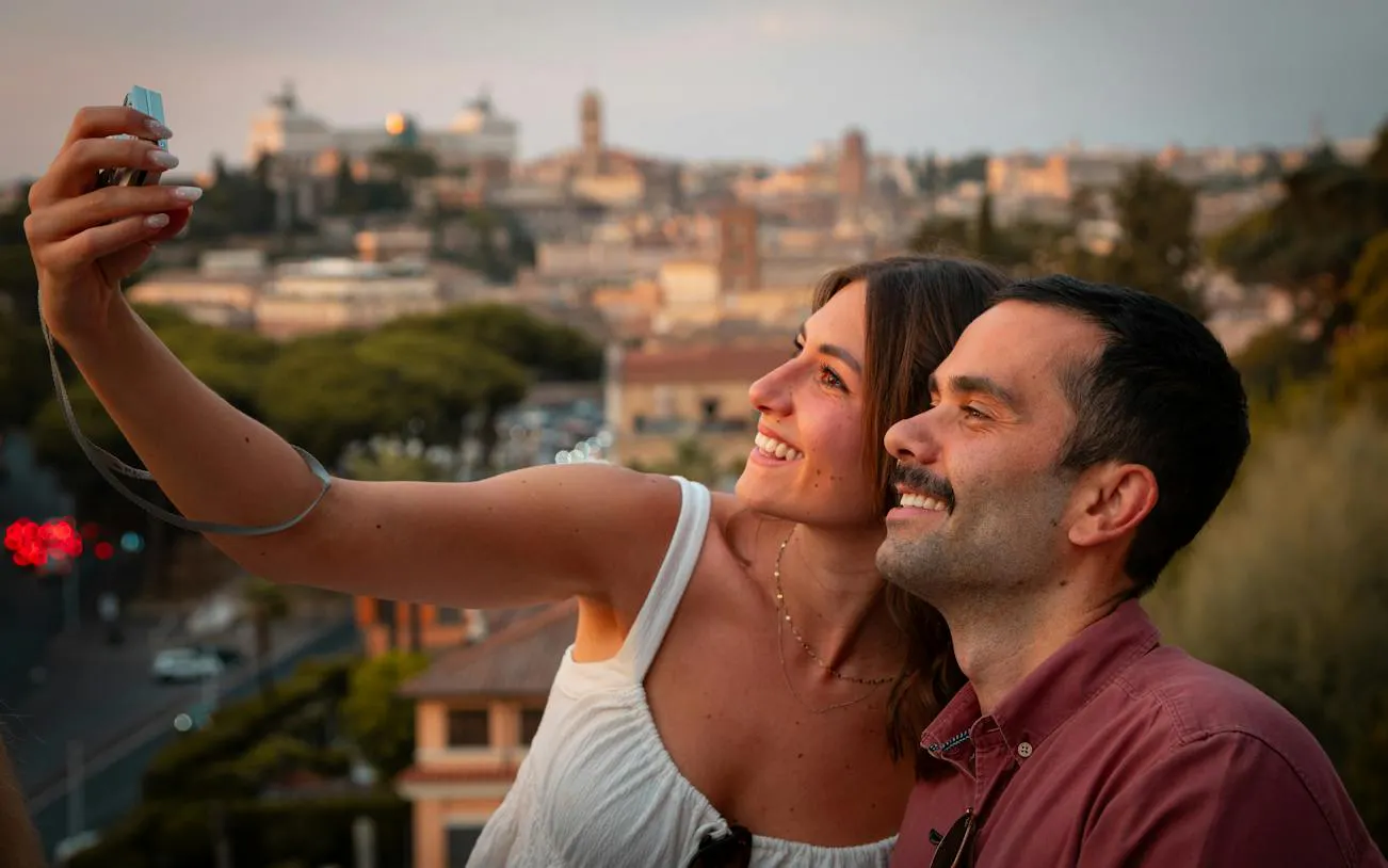 Couple taking a selfie with a panoramic view of Rome during a golf cart tour.