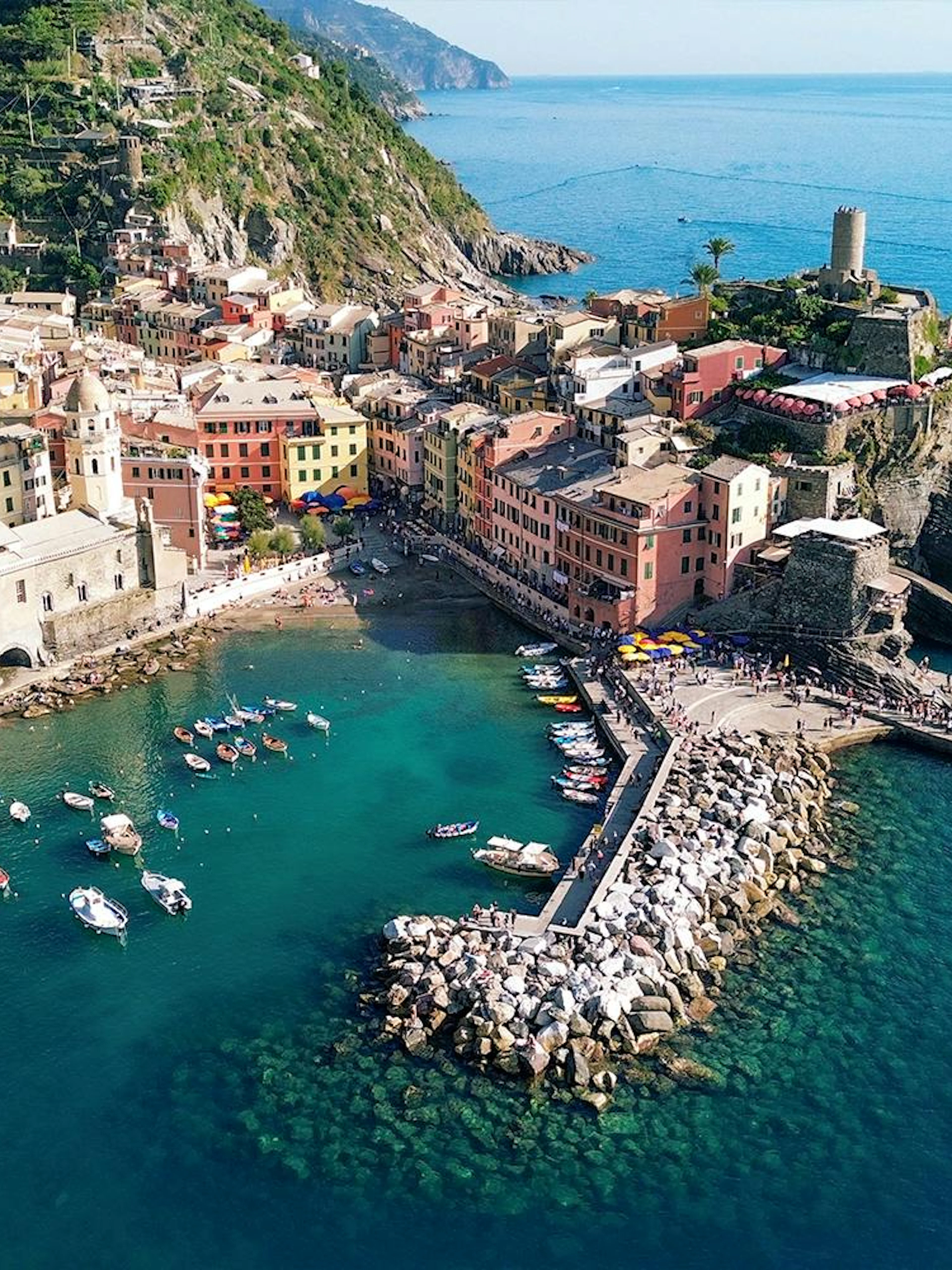 Cinque Terre coastline with colorful buildings and boats in Vernazza harbor.