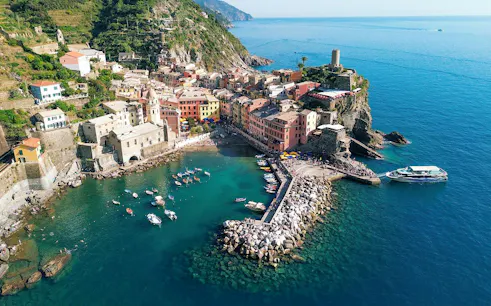 Cinque Terre coastline with colorful buildings and boats in Vernazza harbor.