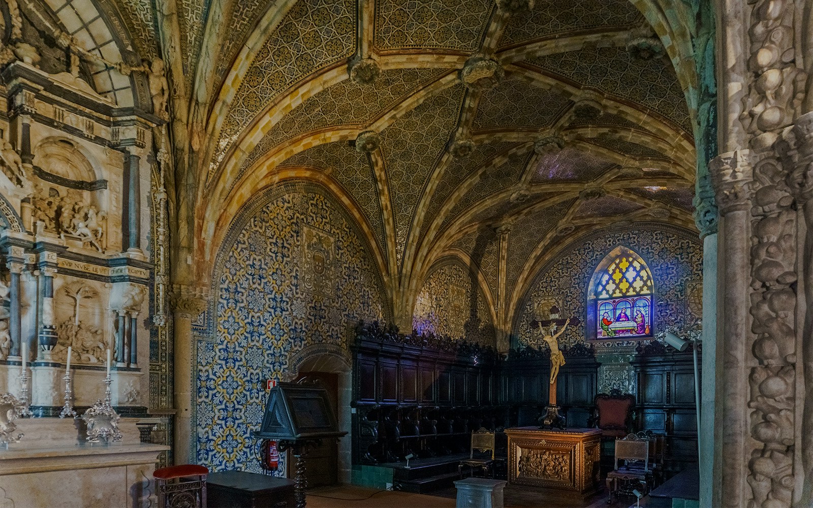Pena Palace chapel interior with ornate ceiling, stained glass window, and altar in Sintra, Portugal.