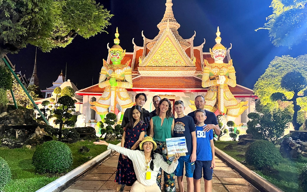 Group in front of Wat Arun temple at night during Bangkok Tuk Tuk tour.