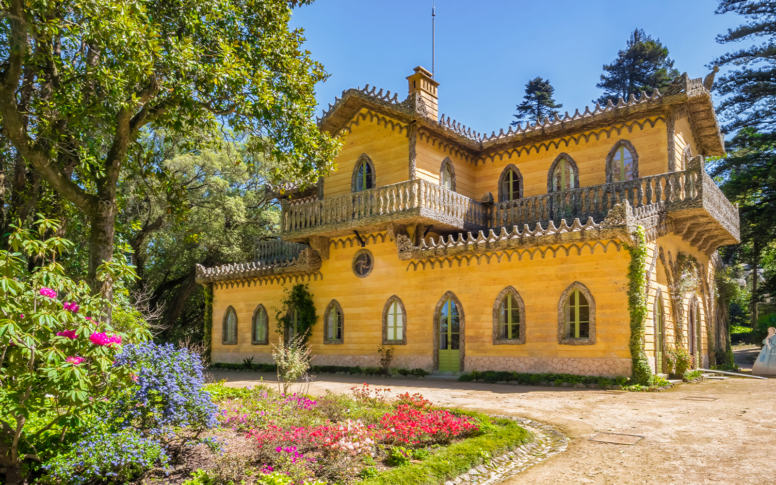 Quinta da Regaleira's yellow villa surrounded by lush gardens in Sintra, Portugal.