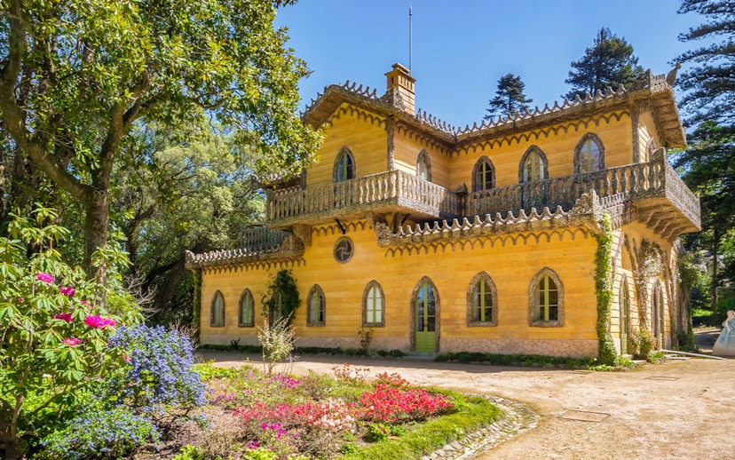 Quinta da Regaleira's yellow villa surrounded by lush gardens in Sintra, Portugal.