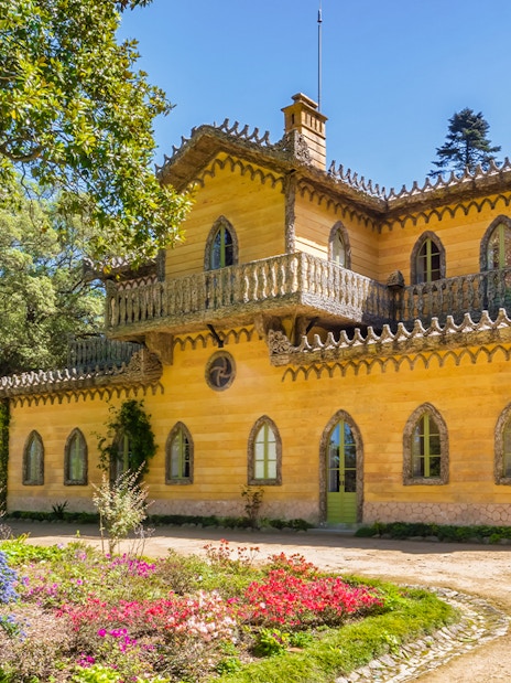 Quinta da Regaleira's yellow villa surrounded by lush gardens in Sintra, Portugal.