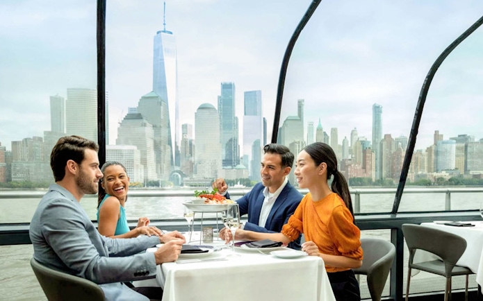 Dining setup on a cruise with a view of New York City skyline.