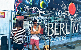 Graffiti-covered Berlin Wall with people and guitar, Berlin Private Walking Tour.