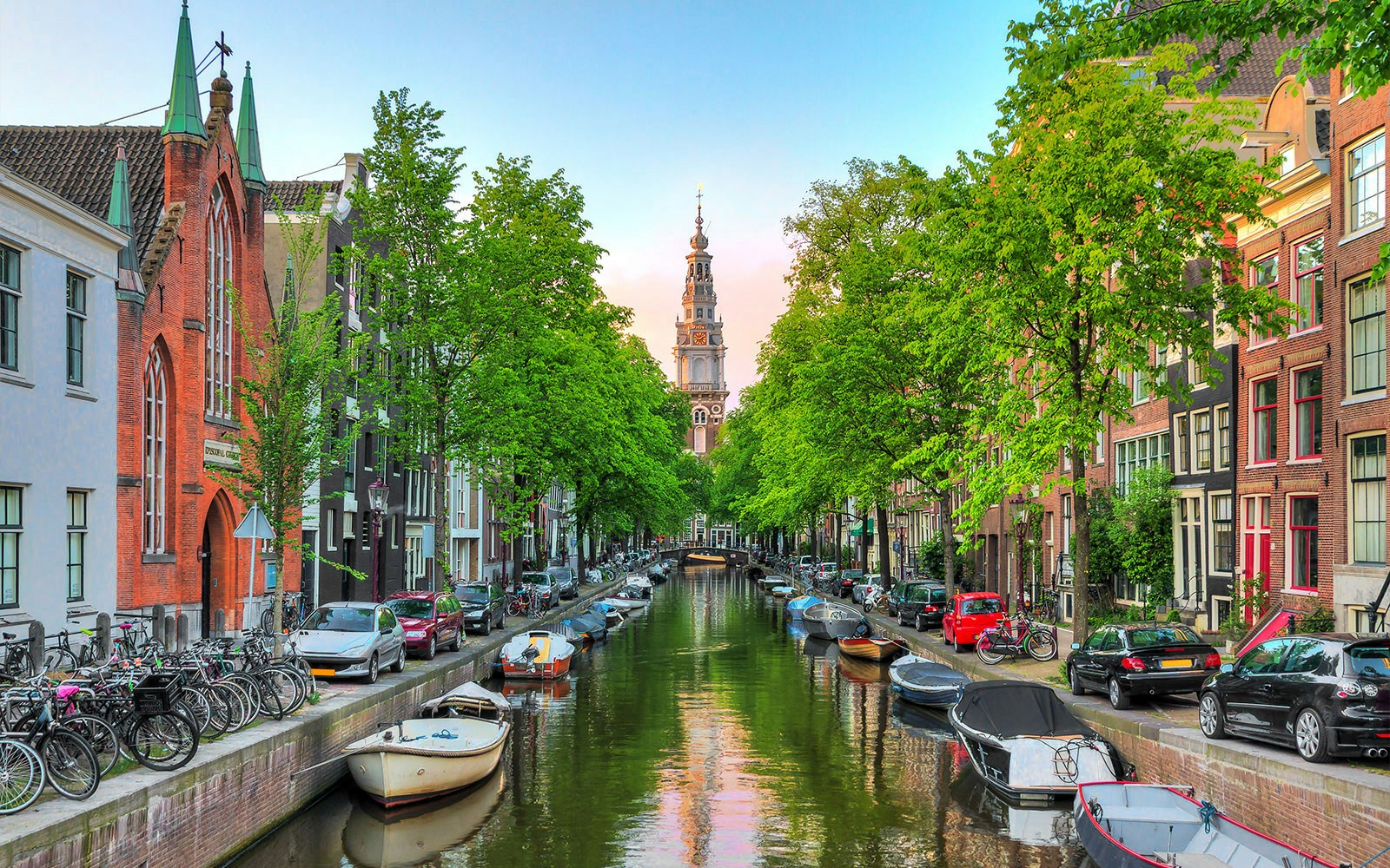Turm der Zuiderkerk am Ende eines Kanals, der von grünen Bäumen gesäumt ist