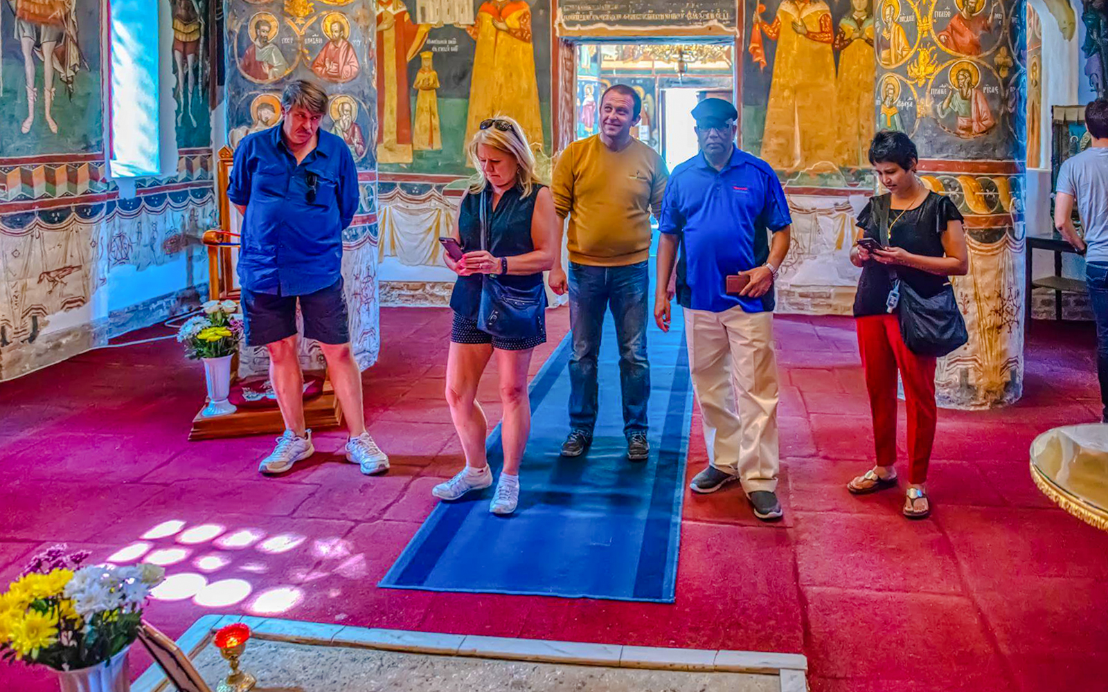 Tour group exploring interior of Snagov Monastery, Romania with frescoes.