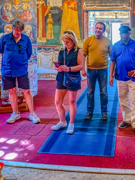 Tour group exploring interior of Snagov Monastery, Romania with frescoes.