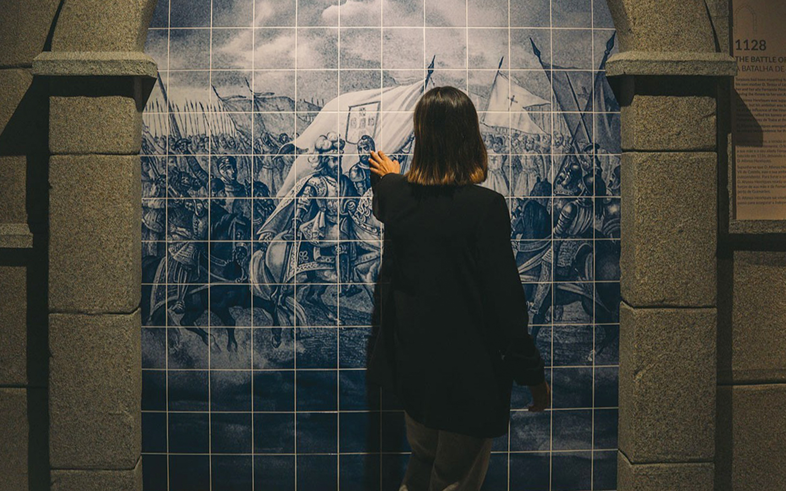 Visitor examining historical tile mural in Porto museum exhibit.