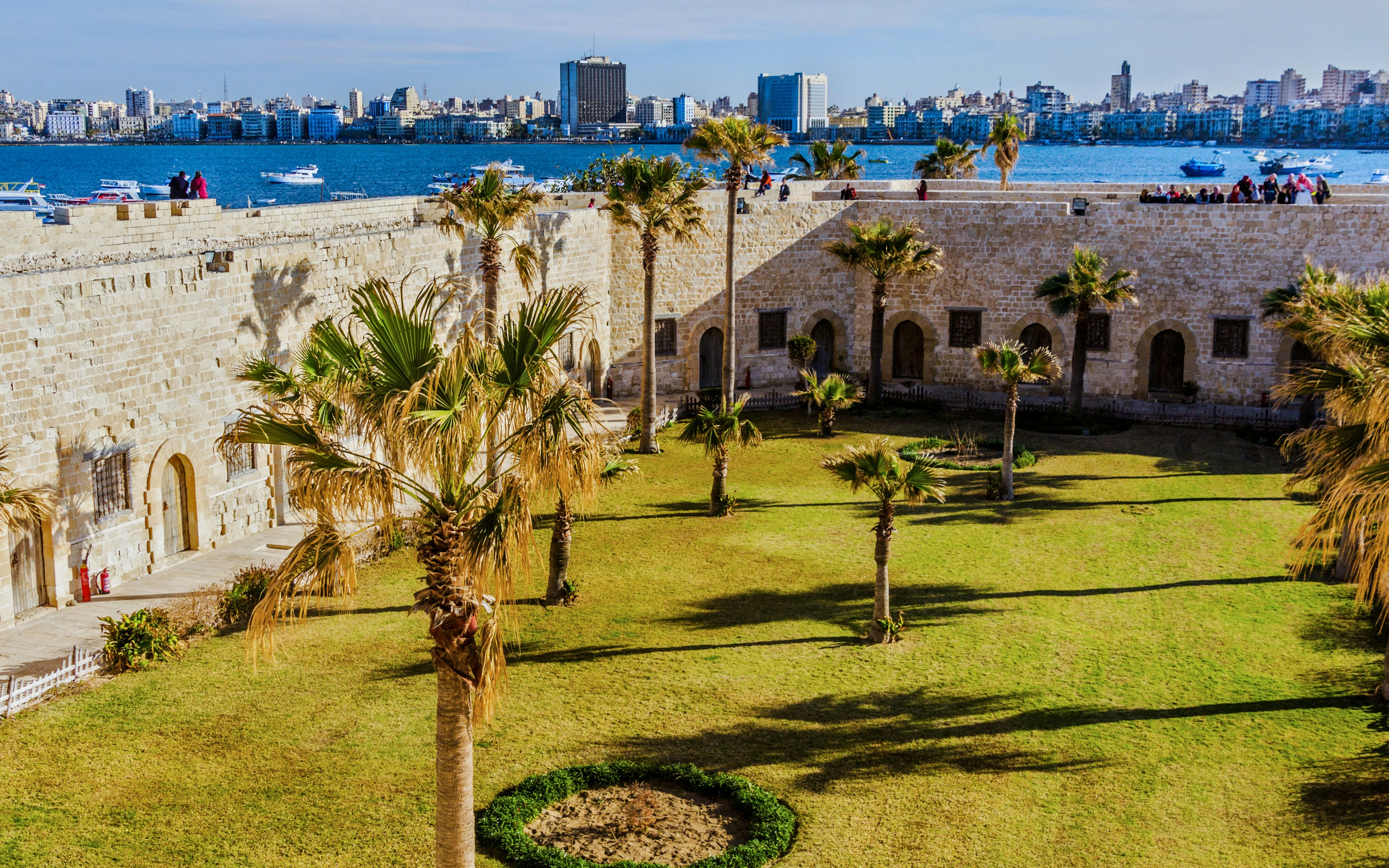 Courtyard of the Citadel of Qaitbay with palm trees and view of Alexandria, Egypt.