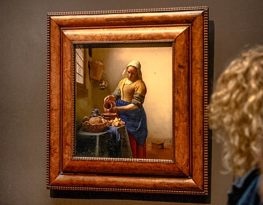 The Milkmaid by Johannes Vermeer displayed in a museum setting.