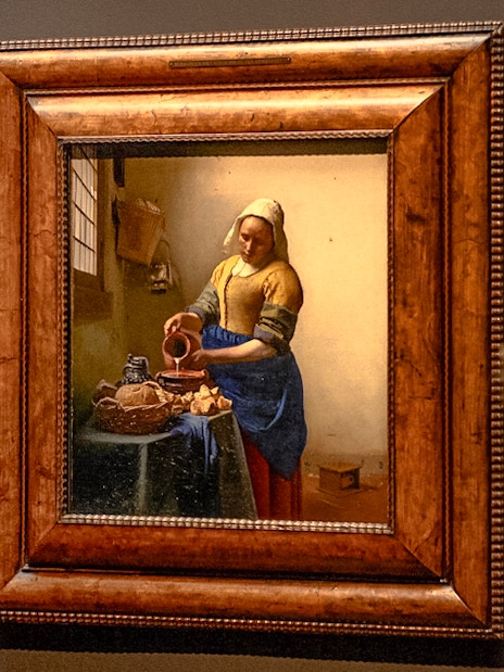 The Milkmaid by Johannes Vermeer displayed in a museum setting.
