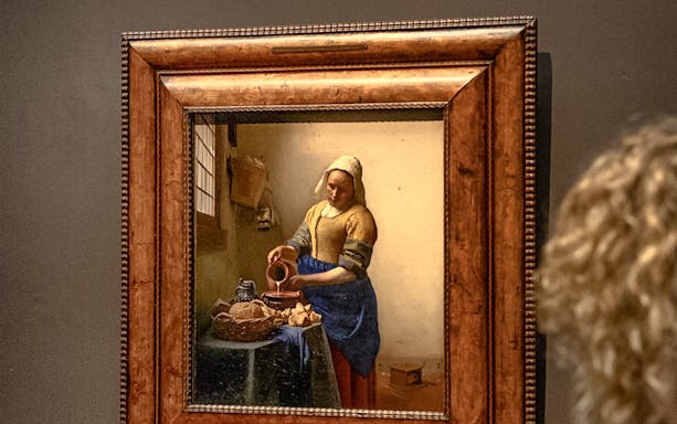 The Milkmaid by Johannes Vermeer displayed in a museum setting.