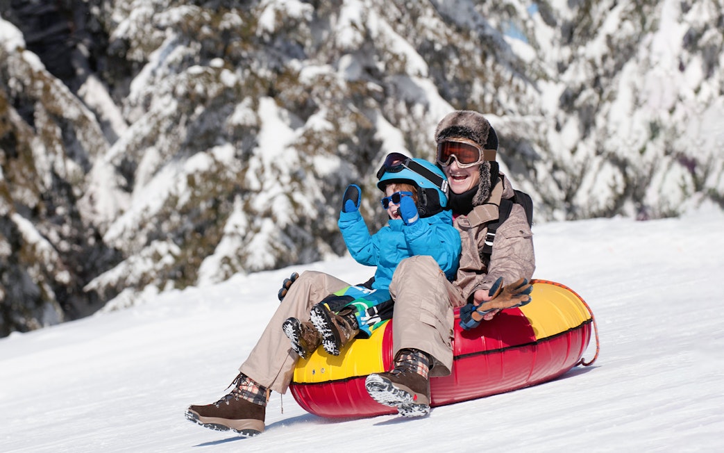 Mother and son tubing down snowy hill, Titlis.