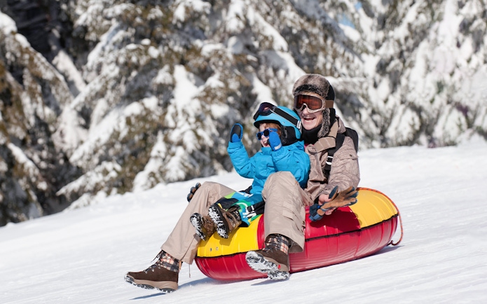 Mother and son tubing down snowy hill, Titlis.