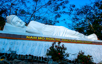 Reclining Buddha statue at Ba Den Mountain, Vietnam, surrounded by trees.