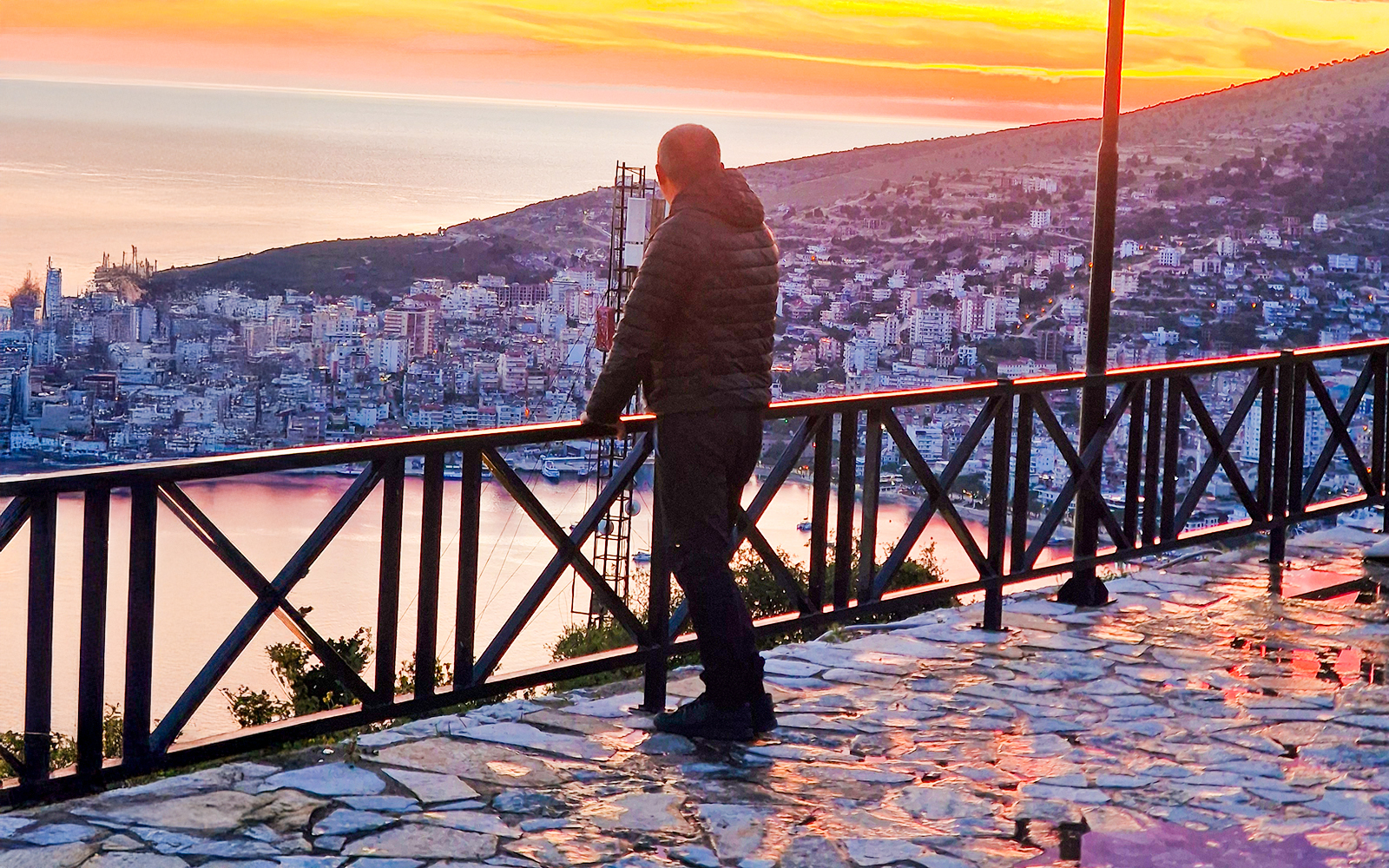 Guest admiring sunset over Sarandë from Lekursi Castle viewpoint.