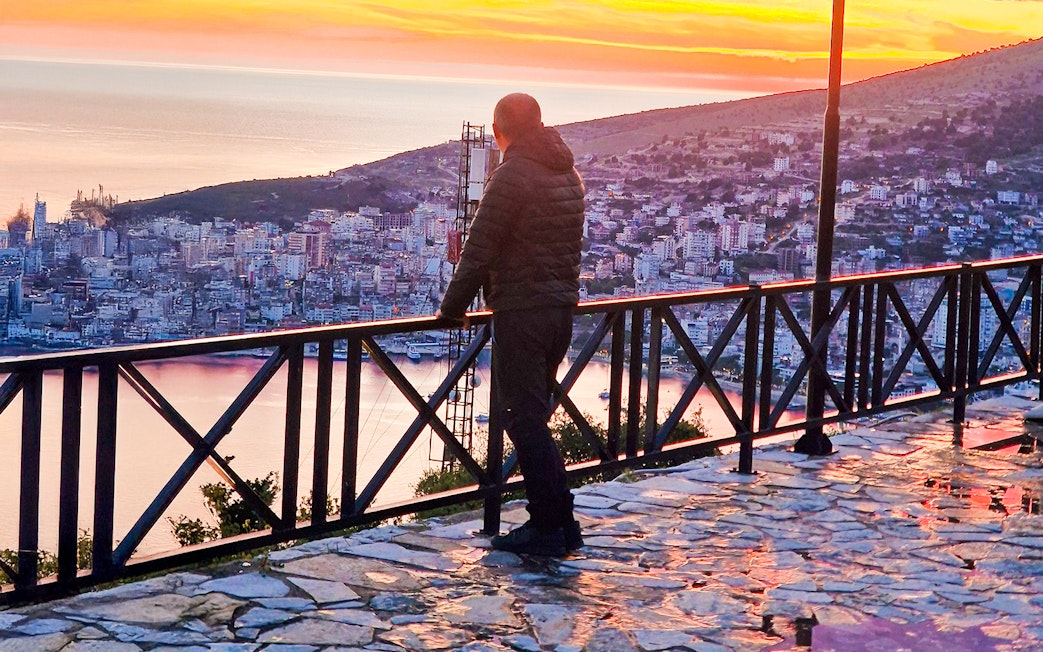 Guest admiring sunset over Sarandë from Lekursi Castle viewpoint.