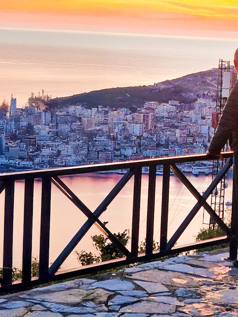 Guest admiring sunset over Sarandë from Lekursi Castle viewpoint.