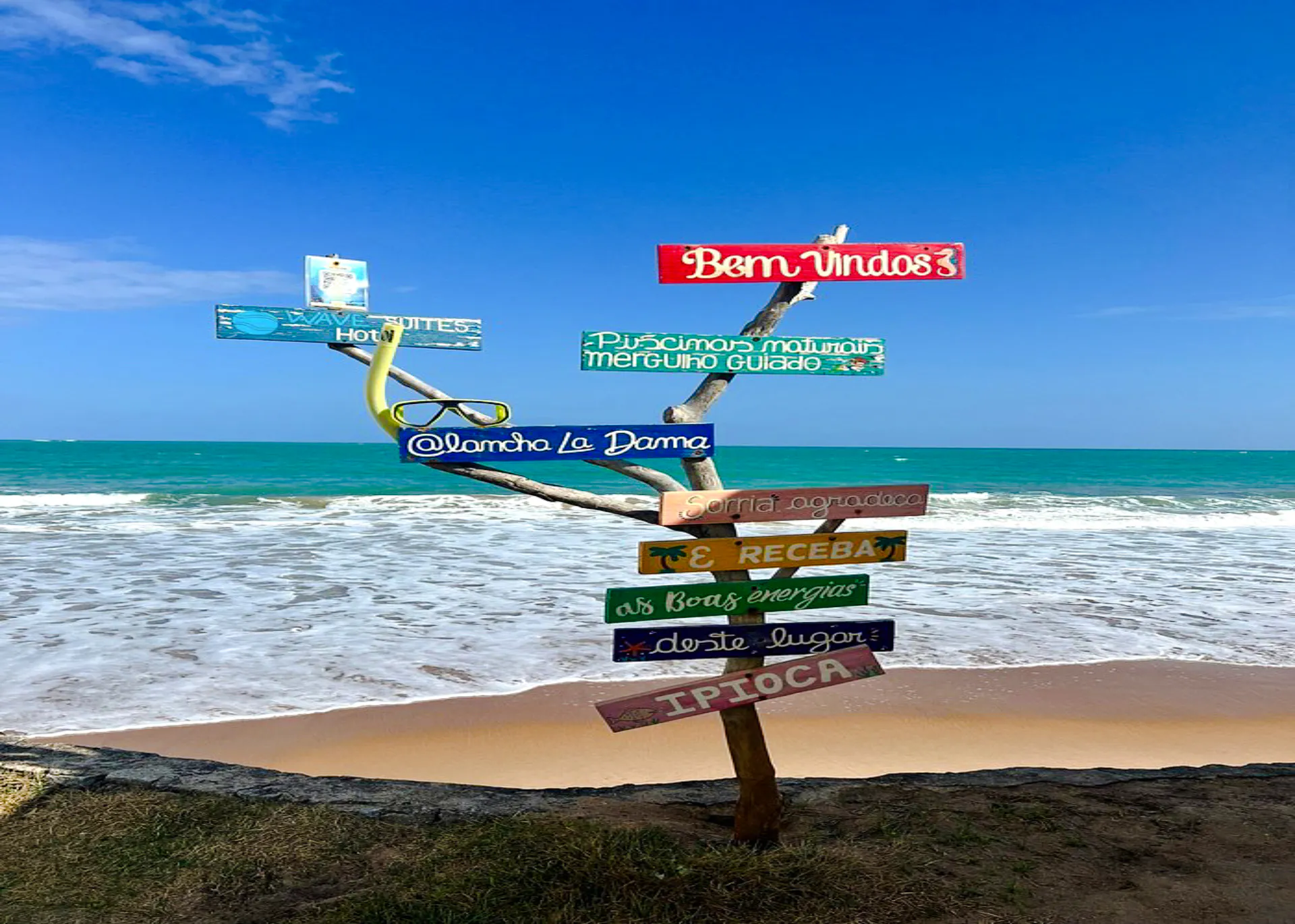 Colorful signpost on Ipioca Beach with ocean view, Maceió, Brazil.