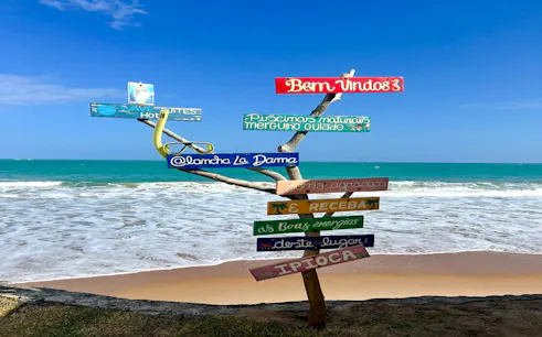 Colorful signpost on Ipioca Beach with ocean view, Maceió, Brazil.
