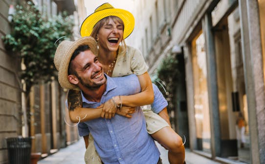 Couple enjoying a playful moment on a European city street.
