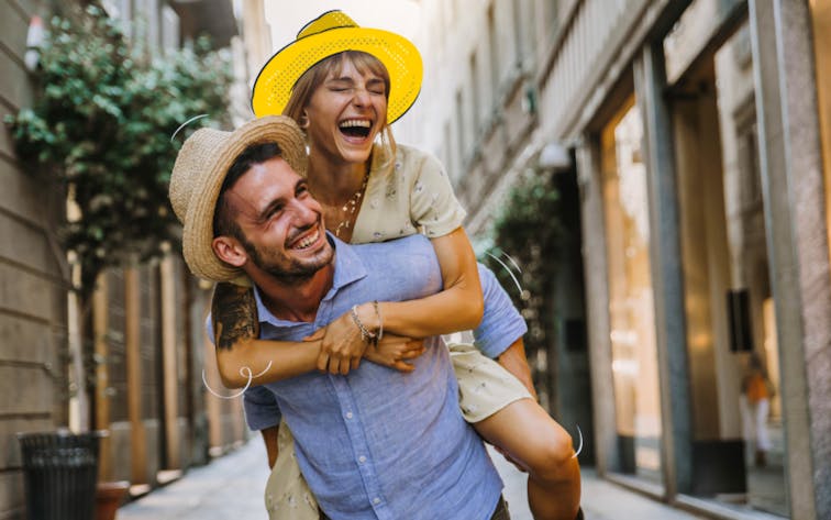 Couple enjoying a playful moment on a European city street.