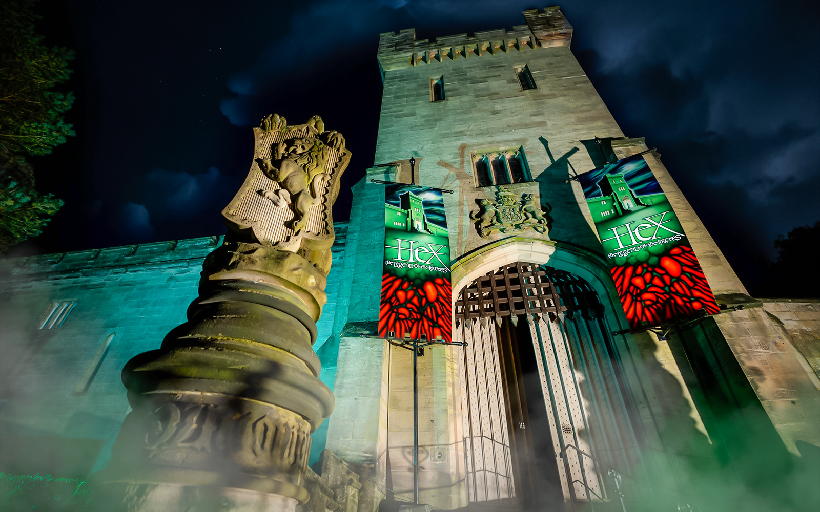Hex Towers entrance at Alton Towers with illuminated banners at night.