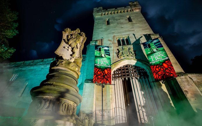 Hex Towers entrance at Alton Towers with illuminated banners at night.