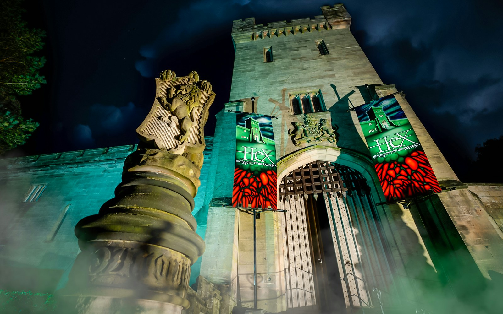 Hex Towers entrance at Alton Towers with illuminated banners at night.