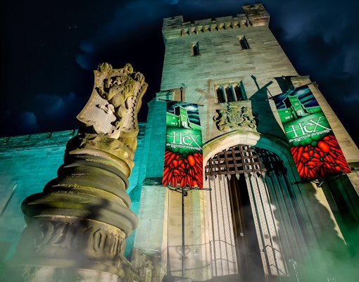 Hex Towers entrance at Alton Towers with illuminated banners at night.