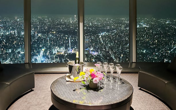Champagne and flowers on table with city view from Sky Restaurant 634 Grand Room Luxe Dinner.